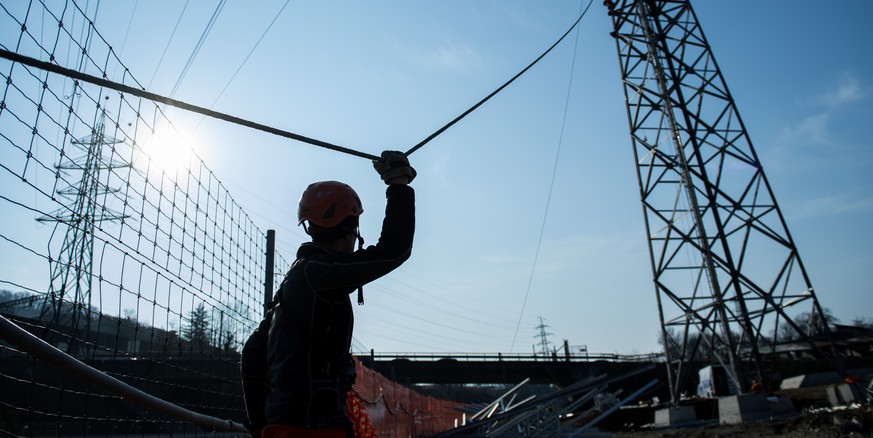 Ein Arbeiter haelt ein Seil waehrend der Konstrukion eines Hochspannungsmasts am Montag 27. Februar 2017, in Vezia im Tessin. Der Strommast des Schweizer Stromnetzes von Swissgrid wird durch die Firma ...